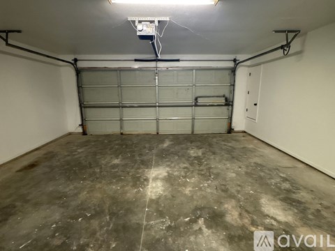 A spacious garage with a concrete floor and a large metal garage door.