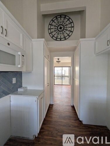 A kitchen with white cabinets and a wooden floor.