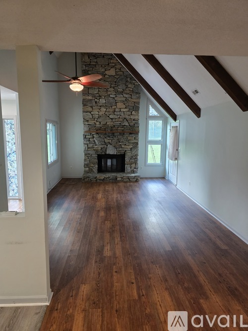 A room with wooden floors and a stone fireplace.