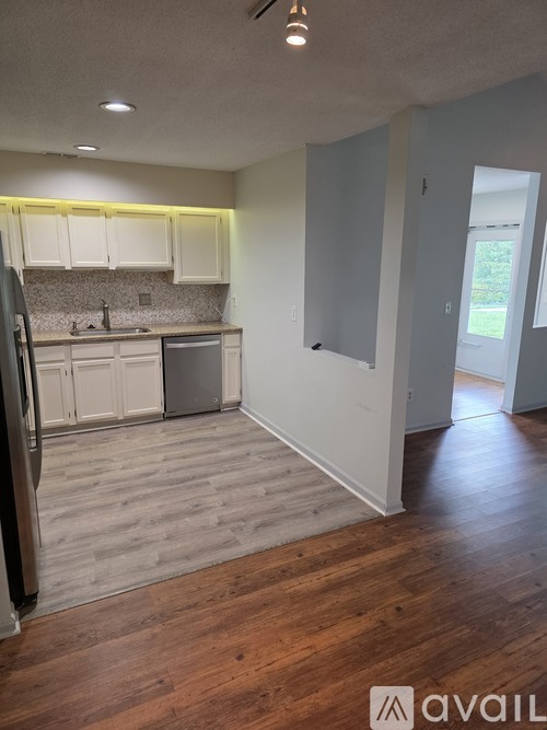 A kitchen with wooden floors and white cabinets.