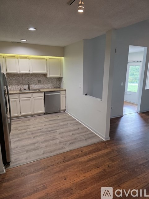 A kitchen with wooden floors and white cabinets.