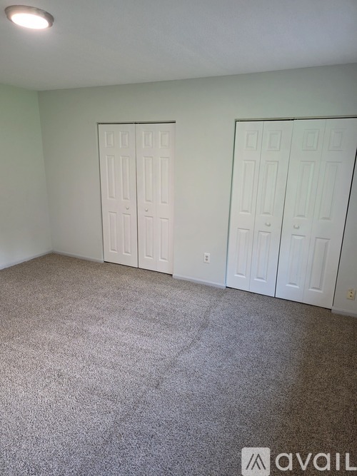 A room with carpeted floor and two white doors.