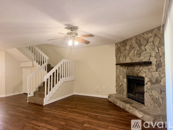A living room with a stone fireplace and a staircase.