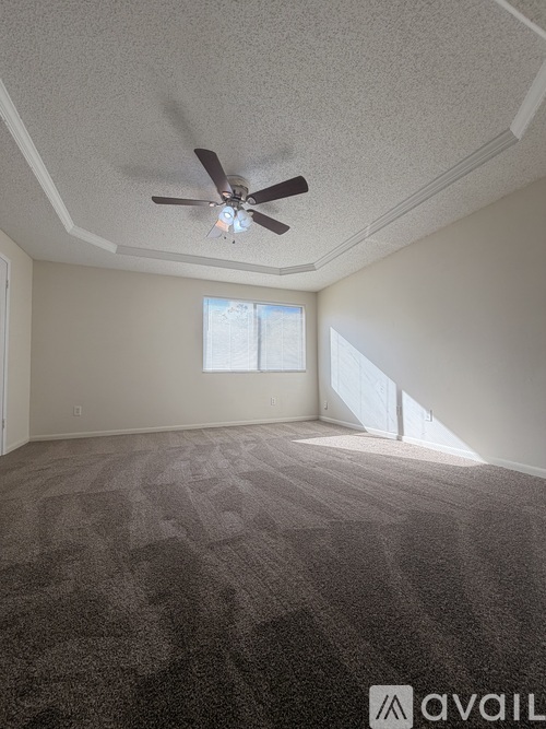 A room with a ceiling fan and carpeted floor.