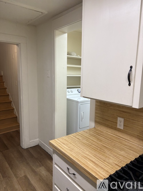 A kitchen with a wooden counter top and white cabinets.