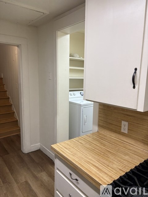 A kitchen with a wooden counter top and white cabinets.