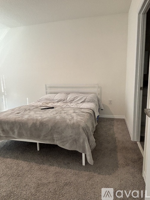 A bedroom with a bed and a carpeted floor.