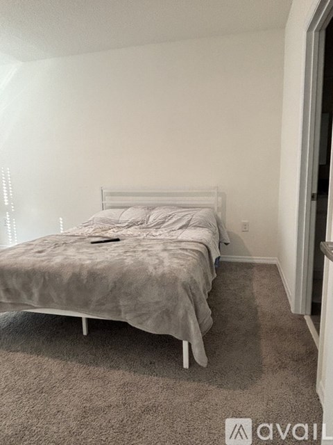 A bedroom with a bed and a carpeted floor.