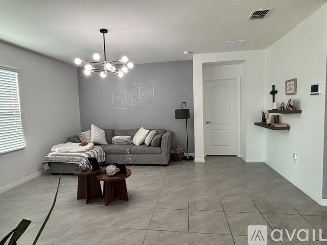 A living room with a grey couch and a chandelier.