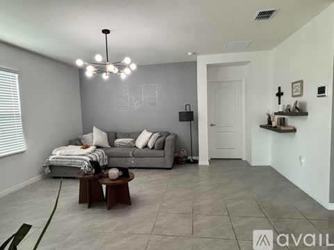 A living room with a grey couch and a chandelier.