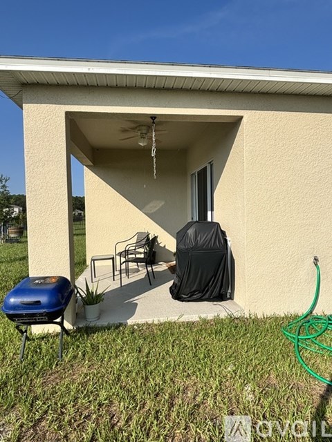 A small building with a blue grill and a black tarp on a chair.
