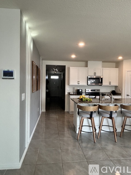 A kitchen with white cabinets and a grey floor.