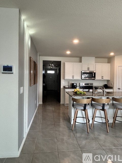 A kitchen with white cabinets and a grey floor.