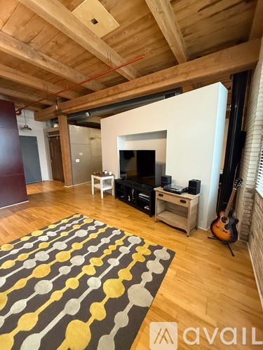 A living room with a wooden floor and a rug with yellow and grey circles.