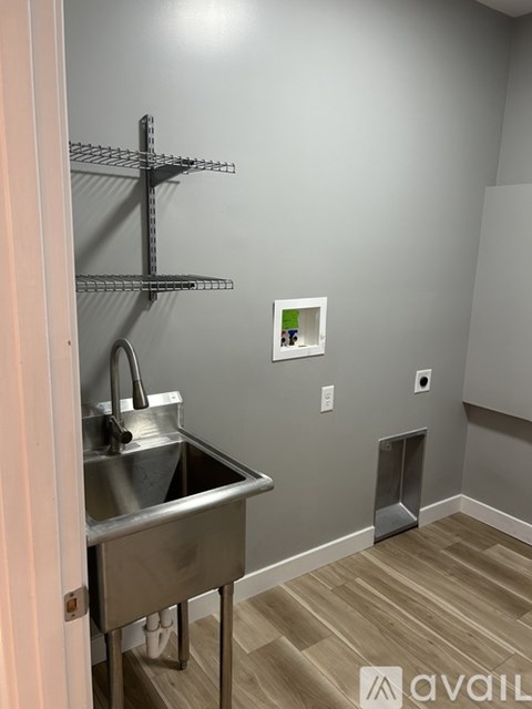 A kitchen with a sink and a wall-mounted shelf.