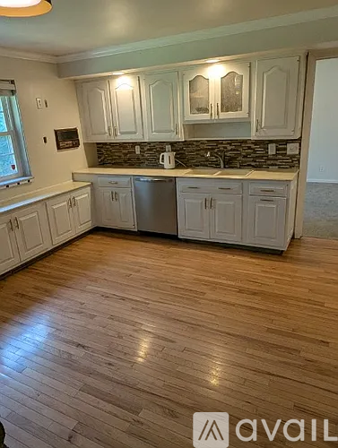 A kitchen with wooden floors and white cabinets.