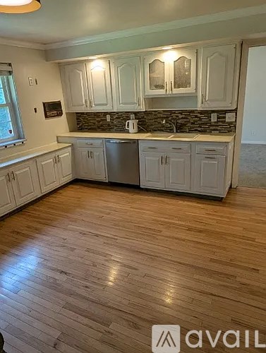 A kitchen with wooden floors and white cabinets.