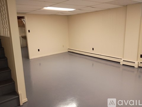 A spacious room with a staircase on the left side.