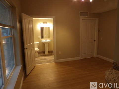A well lit bedroom with a large mirror and a wooden floor.