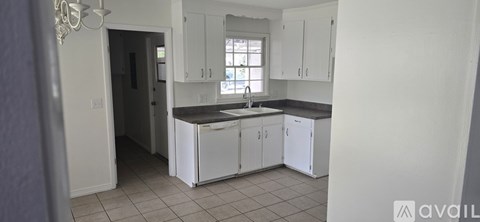 A kitchen with white cabinets and a window.