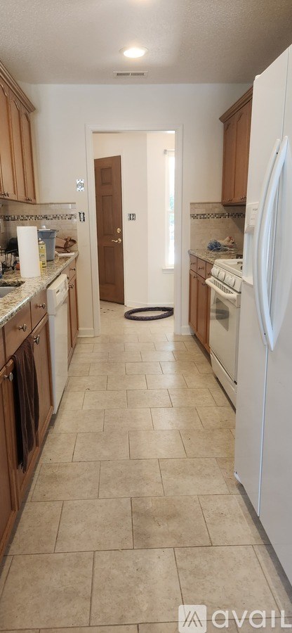 A kitchen with white appliances and wooden cabinets.