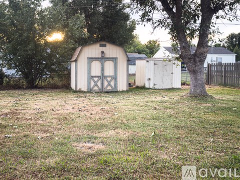 A shed with a blue door is situated in a grassy field.