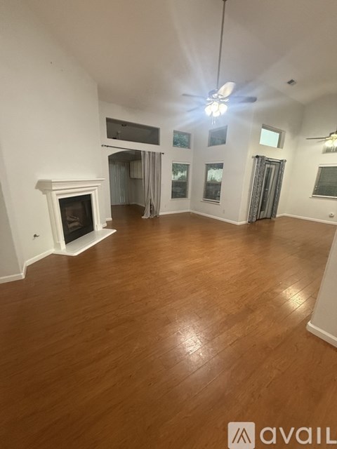 A spacious room with a fireplace and wooden flooring.