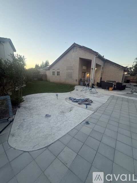 A backyard with a patio and a house in the background.