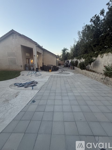 A tiled walkway leads to a building with a patio area in front.