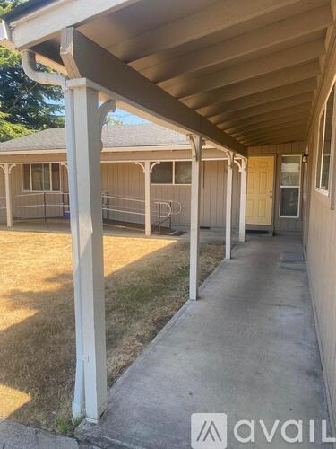 A covered walkway leads to a building with a porch.