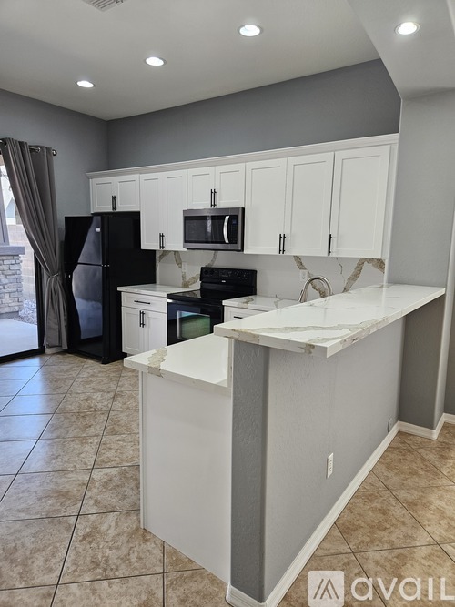 A kitchen with white cabinets and a black refrigerator.