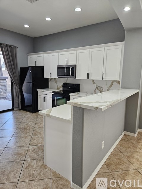A kitchen with white cabinets and a black refrigerator.