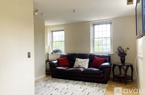 A living room with a black couch and a small table with a vase of flowers on it.