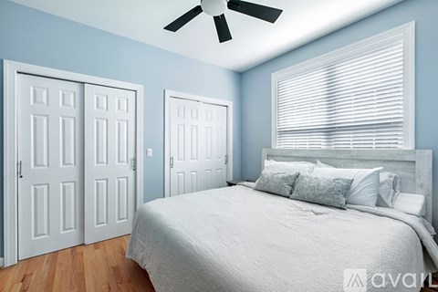 A bedroom with a bed, two doors, and a ceiling fan.