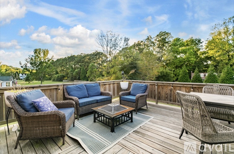 A wooden deck with wicker furniture and a view of trees.