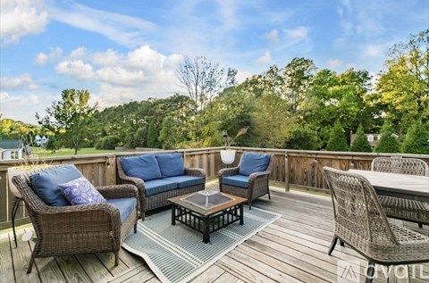 A wooden deck with wicker furniture and a view of trees.