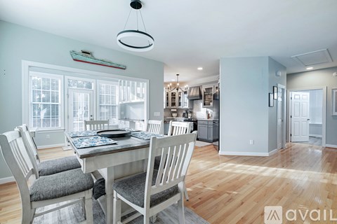 A dining room with a table set for two and a kitchen in the background.