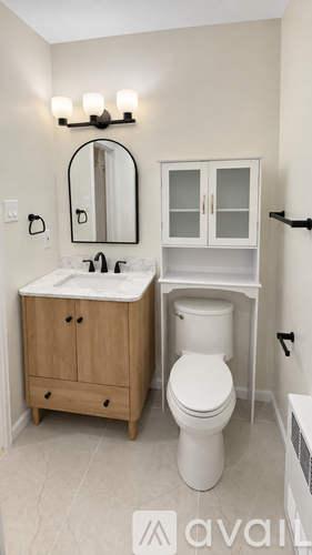 A bathroom with a marble countertop and a round mirror.
