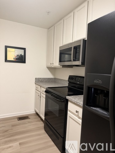A kitchen with black appliances and white cabinets.