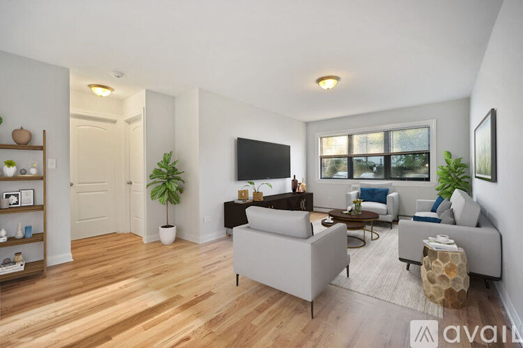 A living room with a grey couch, a wooden floor, and a flat screen TV mounted on the wall.