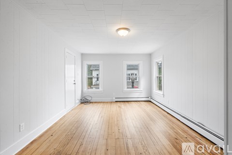 A spacious room with wooden floors and white walls.
