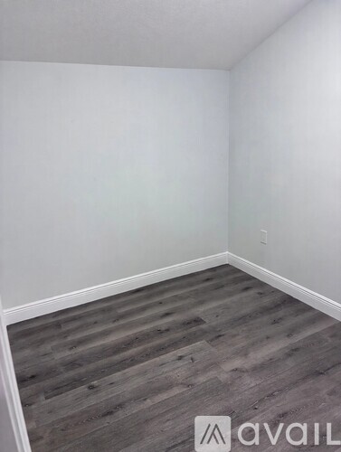 A room with wooden flooring and white walls.