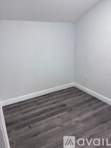 A room with wooden flooring and white walls.