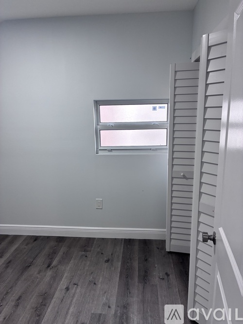 A room with a white door and a window with blinds.