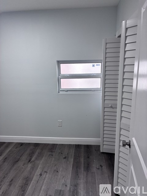A room with a white door and a window with blinds.