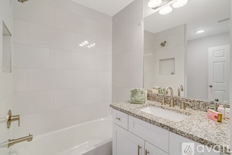 A white bathroom with a tub, sink, and mirror.