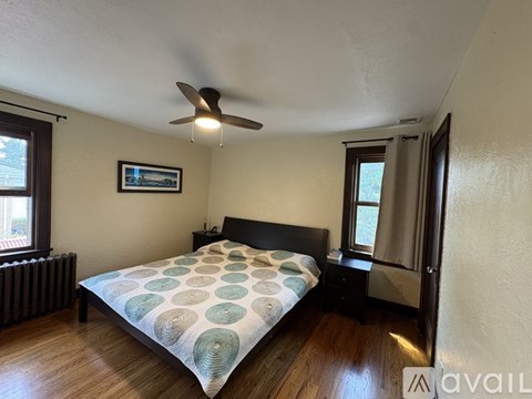 A bedroom with a bed, a ceiling fan, and a window.