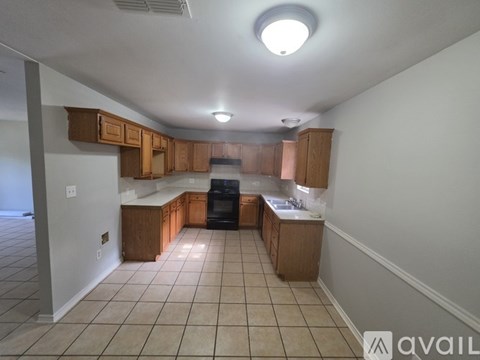 A kitchen with wooden cabinets and a black dishwasher.