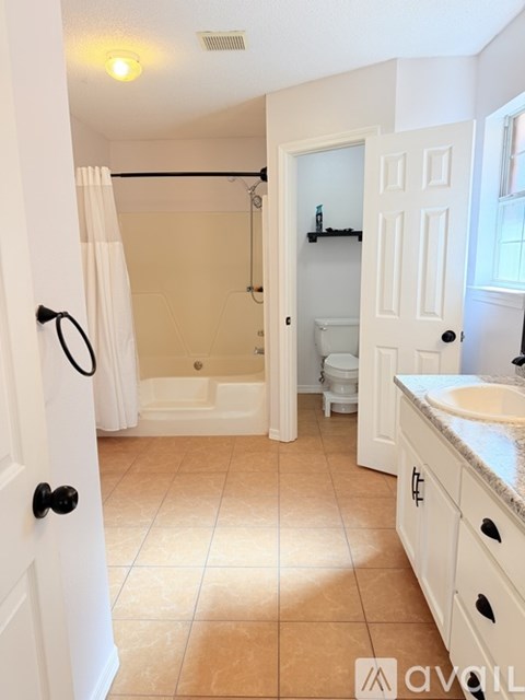 A bathroom with a white door and a tiled floor.