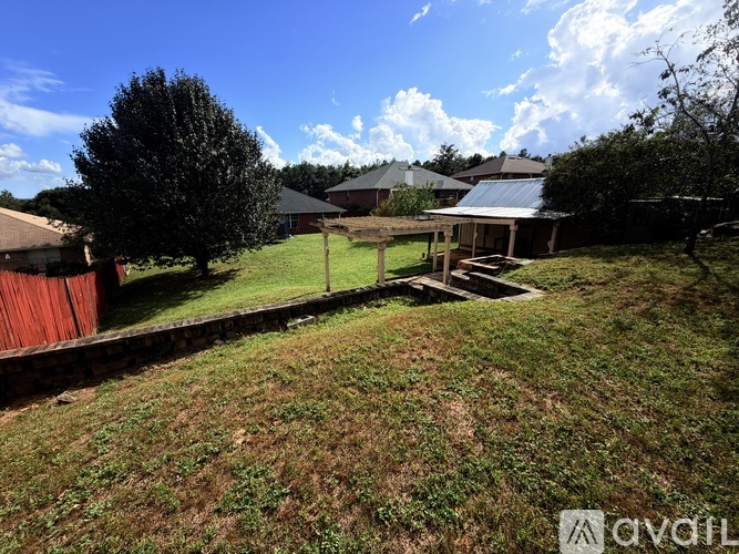 A grassy yard with a house and a tree in the background.